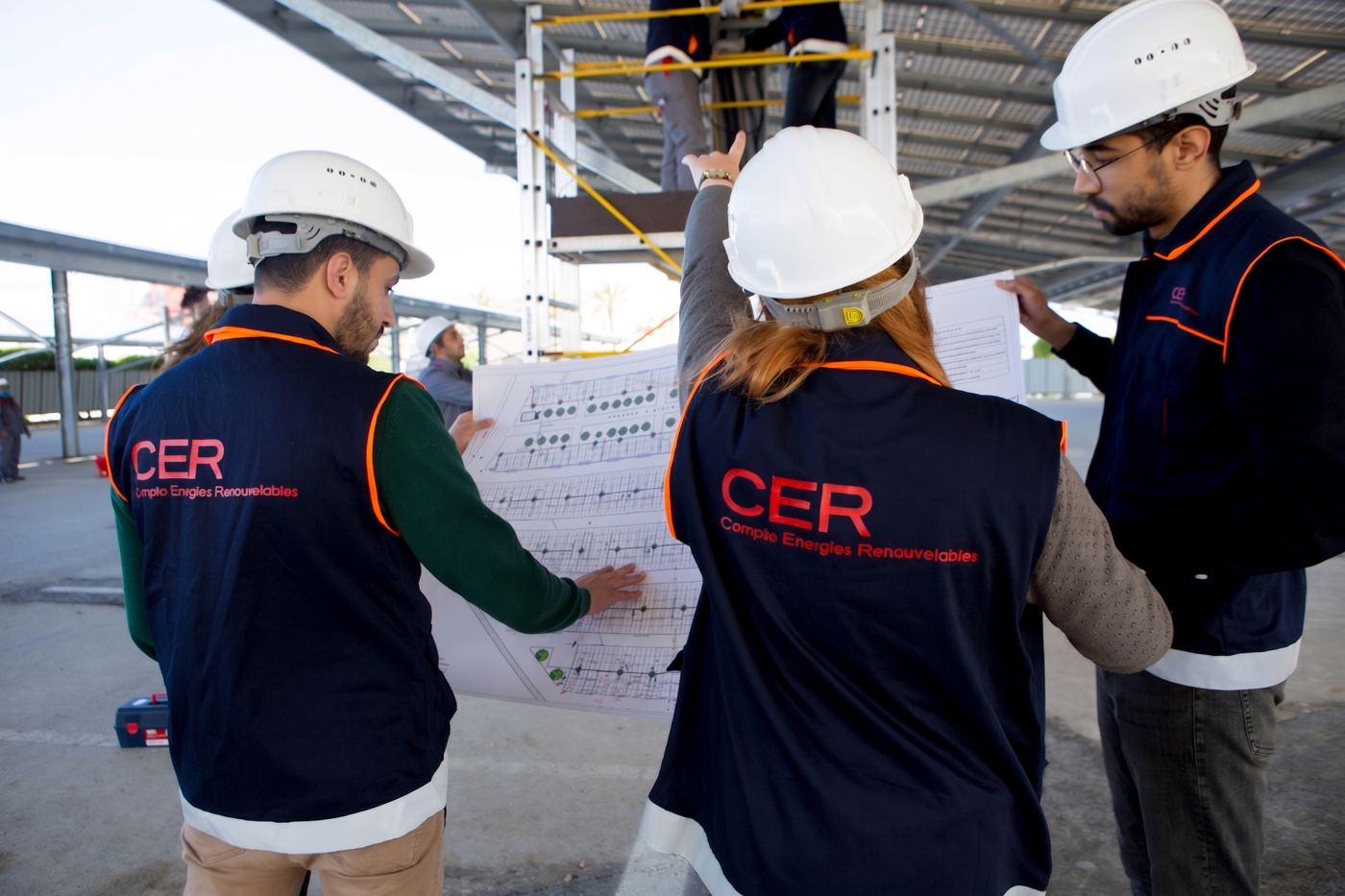 Équipe CER en revue de plans sur une centrale photovoltaïque en ombrière